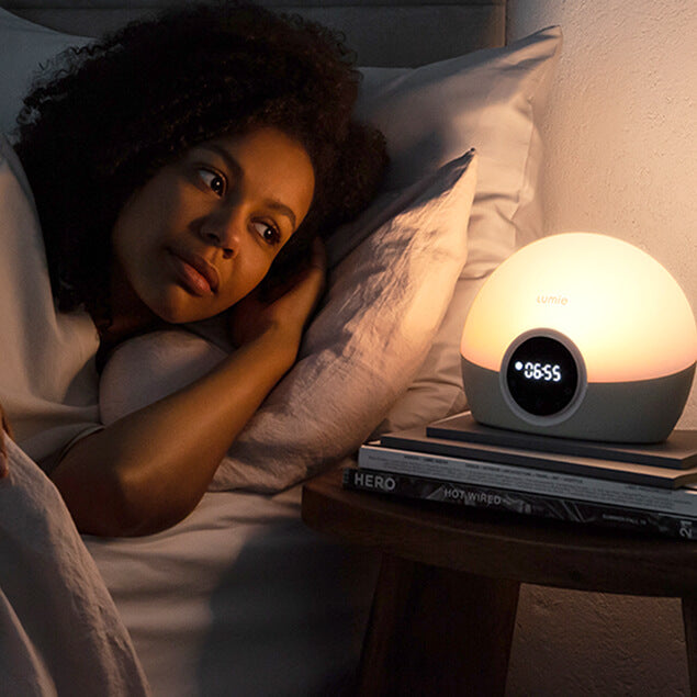 Woman lying in bed with a night light on a bedside table.